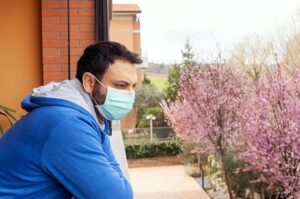 Man with mask using mobile phone during quarantine due to coronavirus